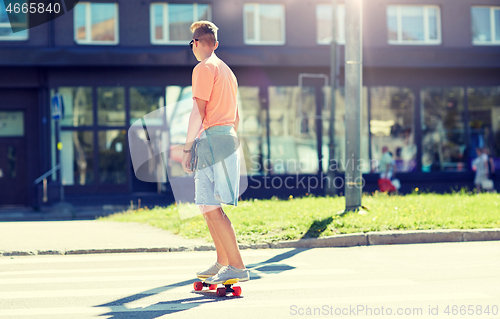 Image of teenage boy on skateboard crossing city crosswalk