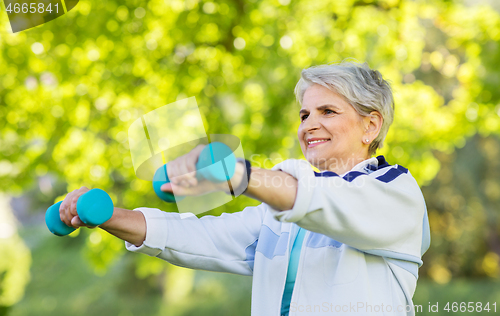 Image of senior woman with dumbbells exercising at park