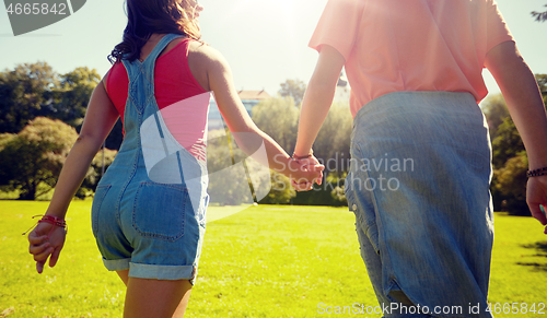 Image of happy teenage couple walking at summer park