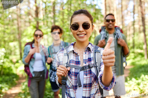 Image of friends with backpacks showing thumbs up in forest