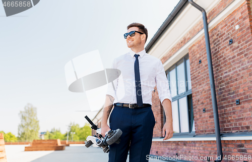 Image of businessman with folding scooter on rooftop