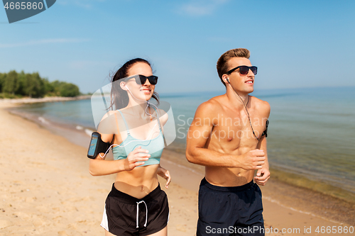 Image of couple with phones and arm bands running on beach