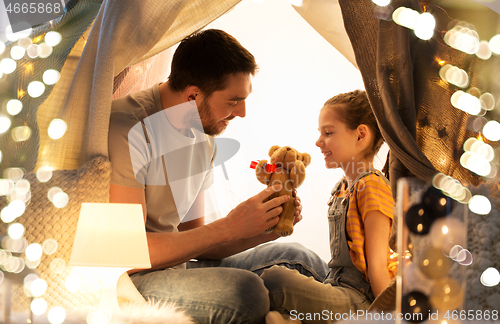 Image of happy family playing with toy in kids tent at home