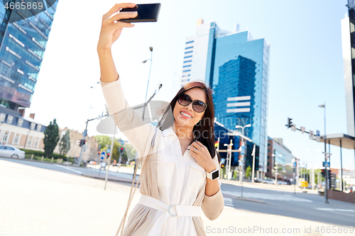 Image of asian woman taking selfie by smartphone in city