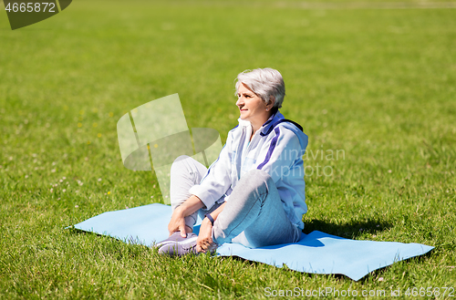 Image of happy senior woman exercising at summer park