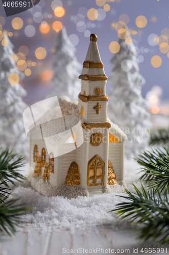 Image of Small church with candles and white trees as snowy landscape