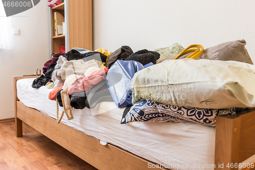 Image of Messy teenager room. Untidy cluttered bed,  dirty clothes.