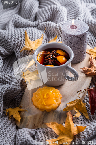 Image of Cosy and soft winter background, with mulled wine, knitted blanket and candle with lemon cake on vintage wooden board. 