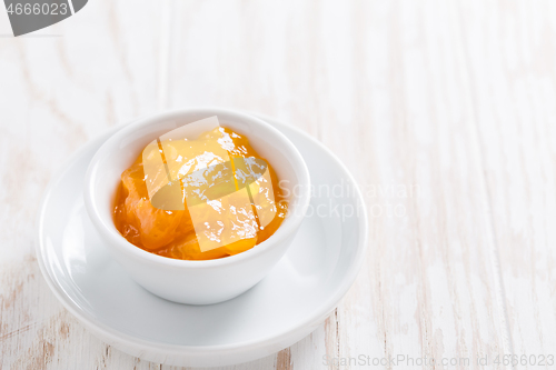 Image of Lemon curd or fruit jelly in small bowl on wooden background