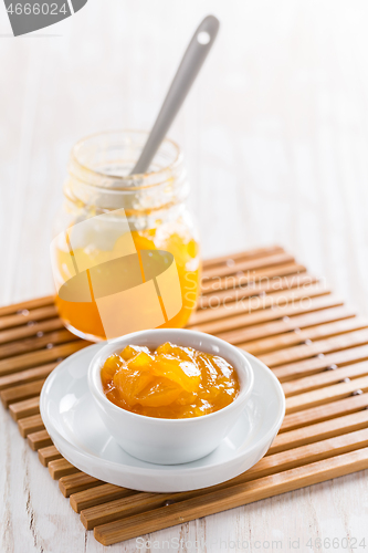 Image of Lemon curd or fruit jelly in small bowl and glass jar on wooden background