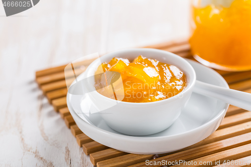 Image of Lemon curd or fruit jelly in small bowl and glass jar on wooden background