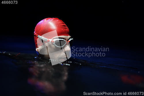 Image of authentic triathlete swimmer having a break during hard training on night