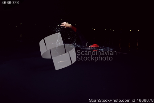 Image of triathlon athlete swimming in dark night wearing wetsuit