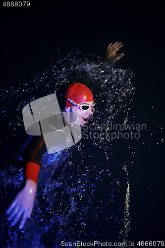 Image of real triathlon athlete swimming in dark night