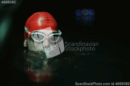 Image of authentic triathlete swimmer having a break during hard training on night neon gel light