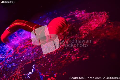 Image of real triathlon athlete swimming in dark night