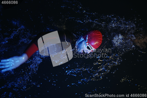 Image of real triathlon athlete swimming in dark night