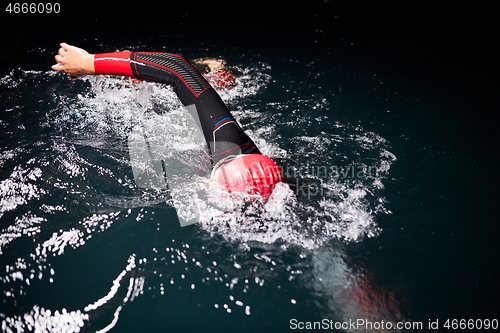 Image of triathlon athlete swimming in dark night wearing wetsuit