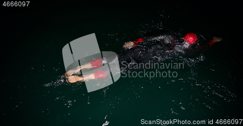 Image of triathlon athlete swimming in dark night wearing wetsuit