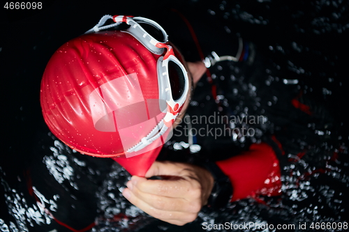 Image of authentic triathlete swimmer having a break during hard training on night