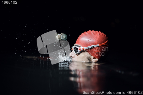 Image of authentic triathlete swimmer having a break during hard training on night