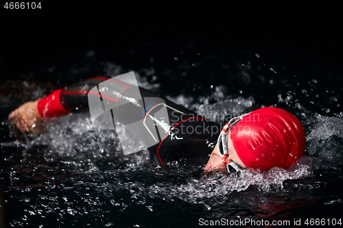 Image of triathlon athlete swimming in dark night wearing wetsuit