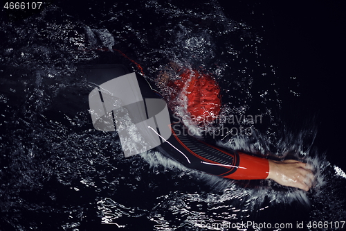 Image of triathlon athlete swimming in dark night wearing wetsuit