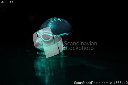 Image of authentic triathlete swimmer having a break during hard training on night neon gel light
