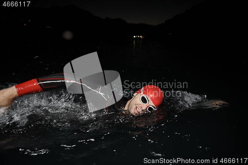 Image of triathlon athlete swimming in dark night wearing wetsuit