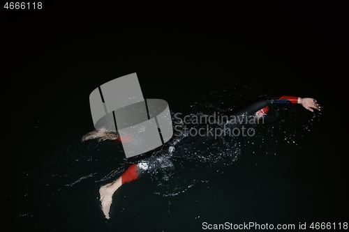 Image of triathlon athlete swimming in dark night wearing wetsuit