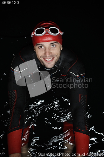 Image of authentic triathlete swimmer having a break during hard training on night