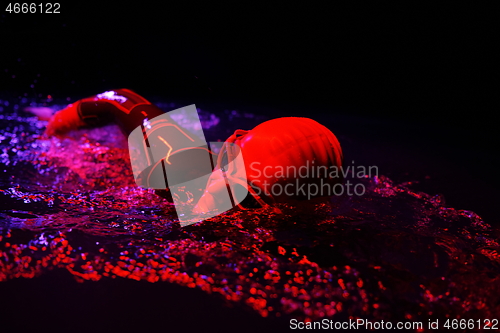 Image of real triathlon athlete swimming in dark night