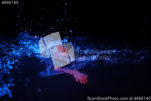 Image of real triathlon athlete swimming in dark night