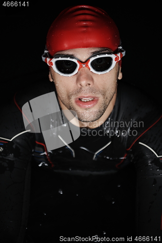 Image of authentic triathlete swimmer having a break during hard training on night