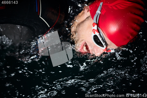 Image of triathlon athlete swimming in dark night wearing wetsuit