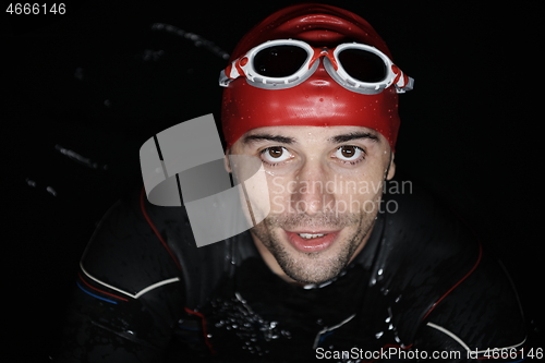 Image of authentic triathlete swimmer having a break during hard training on night