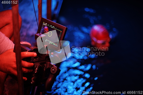 Image of videographer taking action shot of triathlon swimming athlete at night