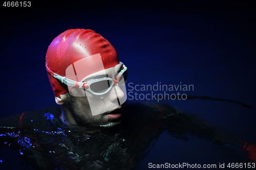 Image of authentic triathlete swimmer having a break during hard training on night