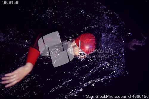 Image of triathlon athlete swimming in dark night wearing wetsuit