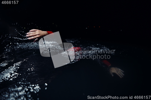 Image of triathlon athlete swimming in dark night wearing wetsuit