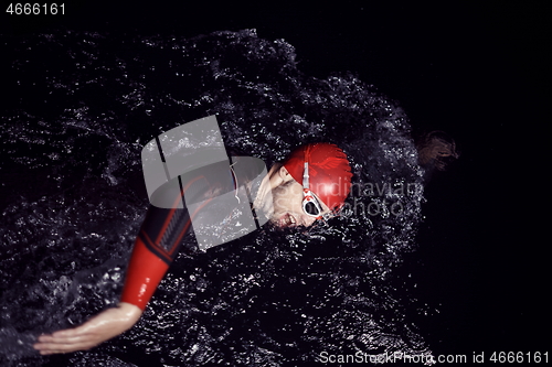 Image of triathlon athlete swimming in dark night wearing wetsuit