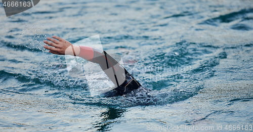 Image of triathlon athlete swimming on lake in sunrise wearing wetsuit