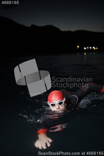 Image of triathlon athlete swimming in dark night wearing wetsuit