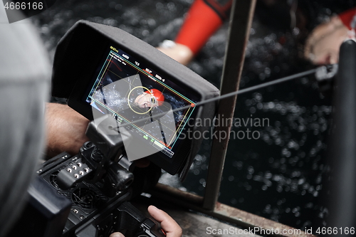 Image of videographer taking action shot of triathlon swimming athlete at night