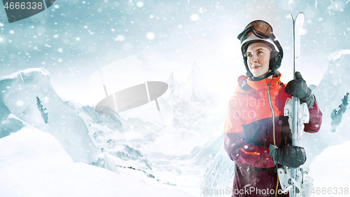 Image of Female skier standing with skies in one hand on background mountain landscape