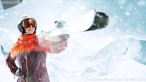 Image of Female skier standing with skies in one hand on background mountain landscape