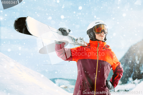 Image of Female skier standing with skies in one hand on background mountain landscape