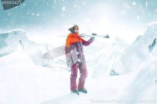 Image of Female skier standing with skies in one hand on background mountain landscape