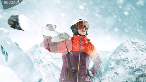 Image of Female skier standing with skies in one hand on background mountain landscape