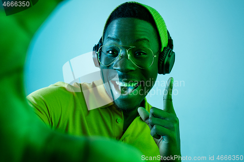 Image of The young handsome hipster man listening music with headphones